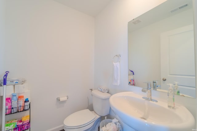 bathroom featuring toilet, a sink, visible vents, and baseboards