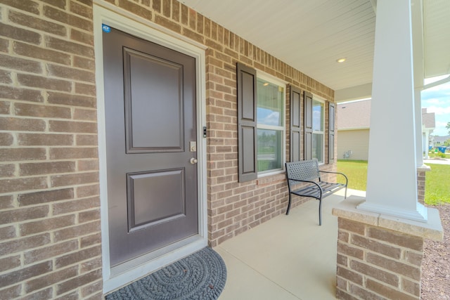 entrance to property with covered porch and brick siding