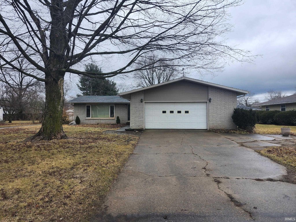 view of front of house with driveway, brick siding, and an attached garage