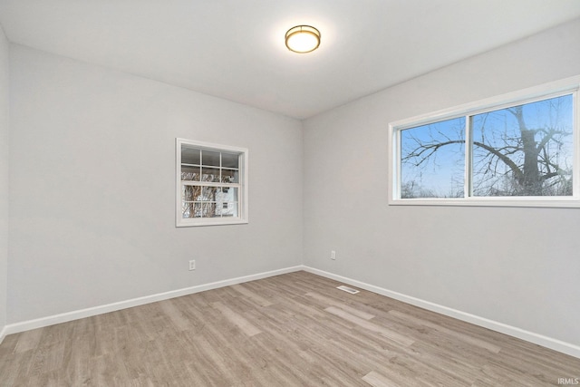 empty room featuring visible vents, light wood-style flooring, and baseboards