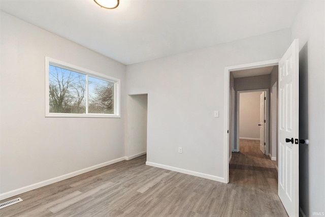 unfurnished bedroom featuring light wood-type flooring, baseboards, and visible vents