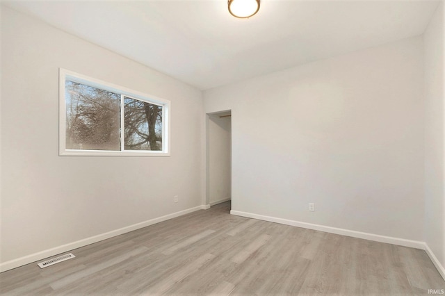 spare room with light wood-style floors, visible vents, and baseboards