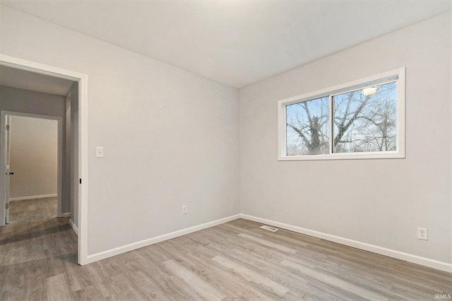 spare room featuring baseboards, visible vents, and light wood finished floors