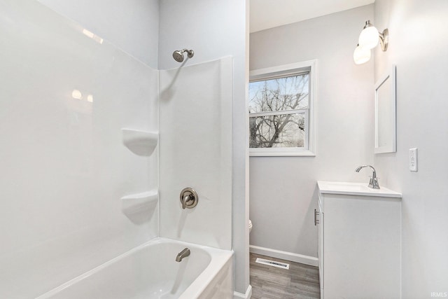 full bathroom featuring wood finished floors, visible vents, vanity, baseboards, and shower / bathing tub combination