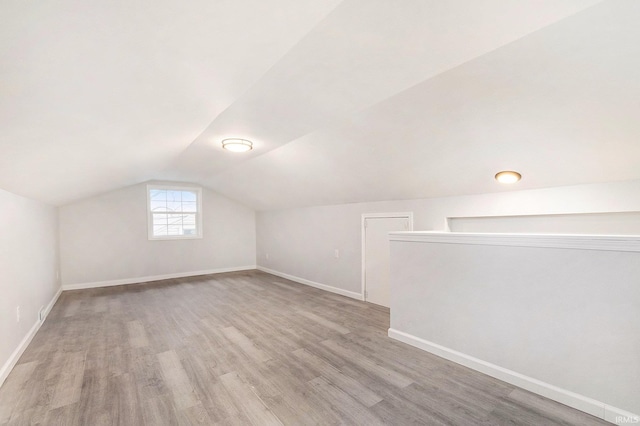 additional living space featuring vaulted ceiling, wood finished floors, and baseboards