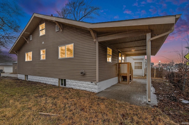 view of side of property featuring a carport, fence, and a lawn