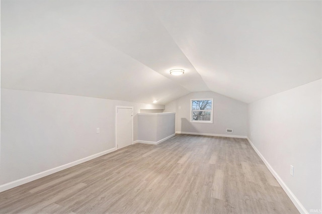 additional living space featuring lofted ceiling, light wood-style floors, visible vents, and baseboards