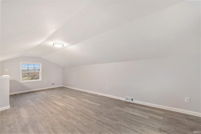 bonus room featuring baseboards, vaulted ceiling, and wood finished floors