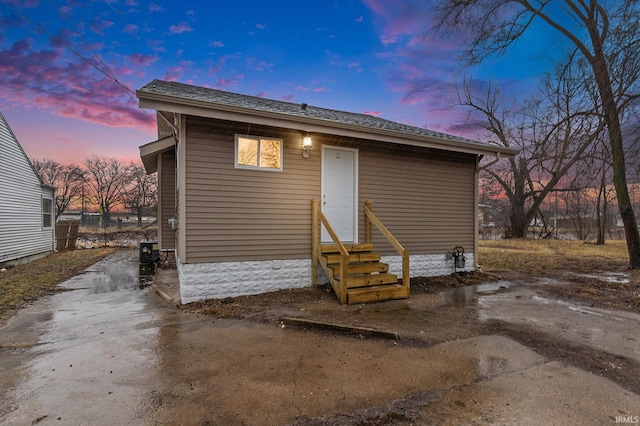 back of house with entry steps and roof with shingles