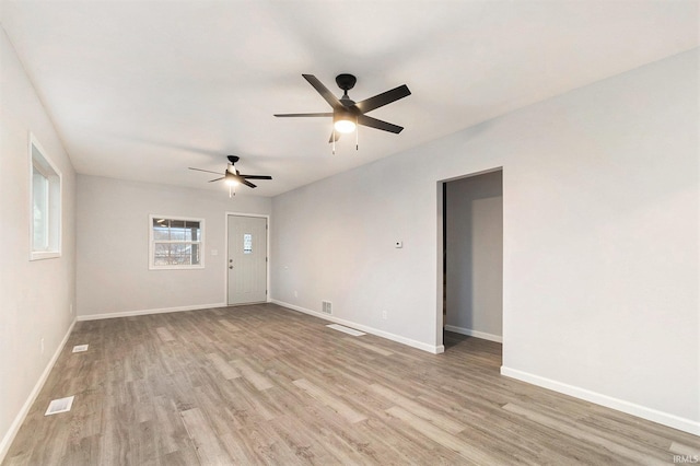 empty room with light wood-style floors, visible vents, baseboards, and ceiling fan