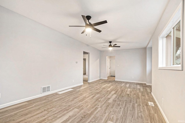 spare room with a ceiling fan, light wood-type flooring, visible vents, and baseboards