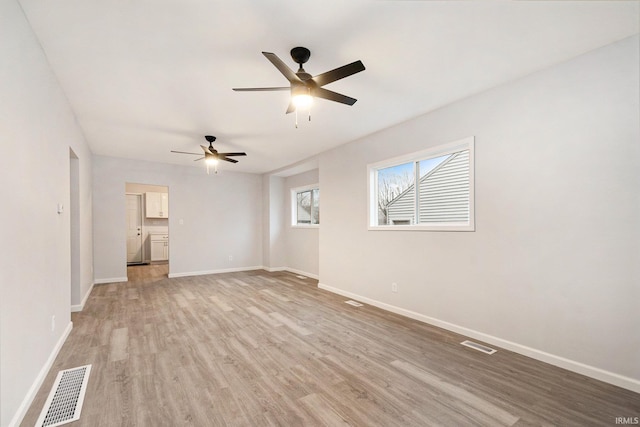 unfurnished living room with light wood-style floors, baseboards, visible vents, and ceiling fan