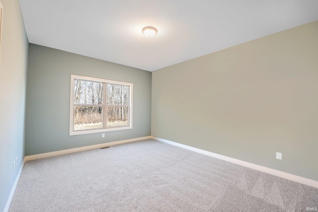 carpeted spare room featuring visible vents and baseboards