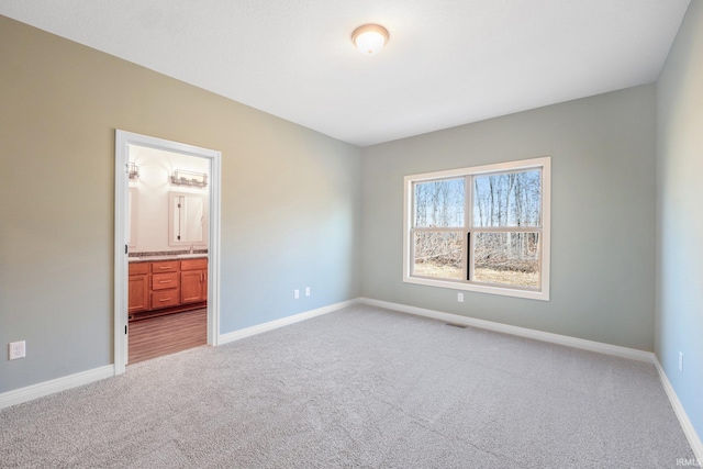 unfurnished bedroom featuring baseboards, connected bathroom, visible vents, and light colored carpet