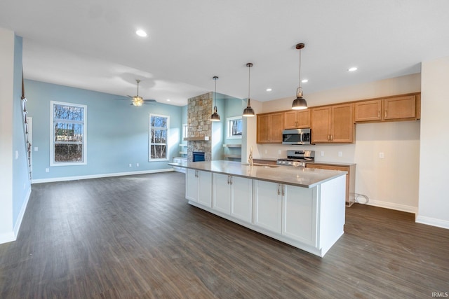 kitchen featuring baseboards, ceiling fan, open floor plan, dark wood-style flooring, and stainless steel appliances