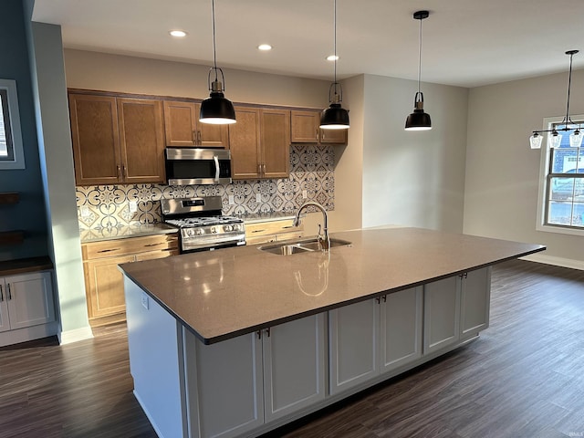 kitchen featuring appliances with stainless steel finishes, dark wood finished floors, a kitchen island with sink, and a sink