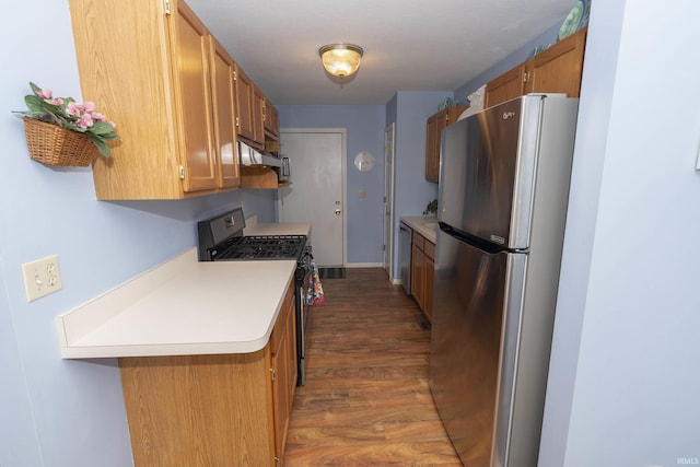 kitchen with dark wood-style floors, brown cabinets, light countertops, appliances with stainless steel finishes, and baseboards