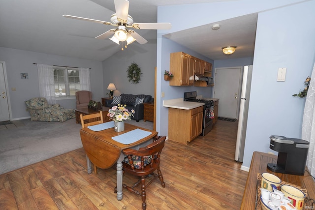 dining space featuring vaulted ceiling, baseboards, light wood-style flooring, and a ceiling fan