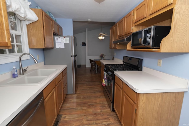 kitchen with under cabinet range hood, stainless steel appliances, a sink, a ceiling fan, and dark wood-style floors