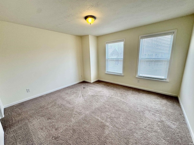 carpeted empty room with a textured ceiling and baseboards