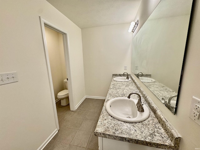 bathroom featuring toilet, baseboards, and a sink