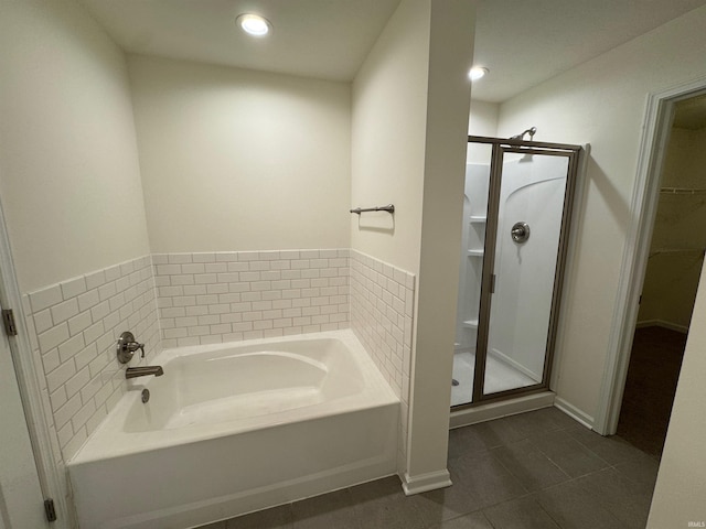 full bathroom with a stall shower, a spacious closet, a garden tub, and tile patterned floors