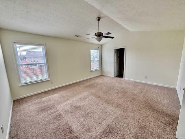 unfurnished room with a ceiling fan, light carpet, vaulted ceiling, a textured ceiling, and baseboards