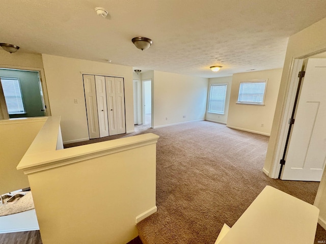 carpeted spare room with a textured ceiling and baseboards