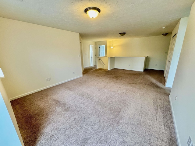 unfurnished room with carpet, baseboards, and a textured ceiling