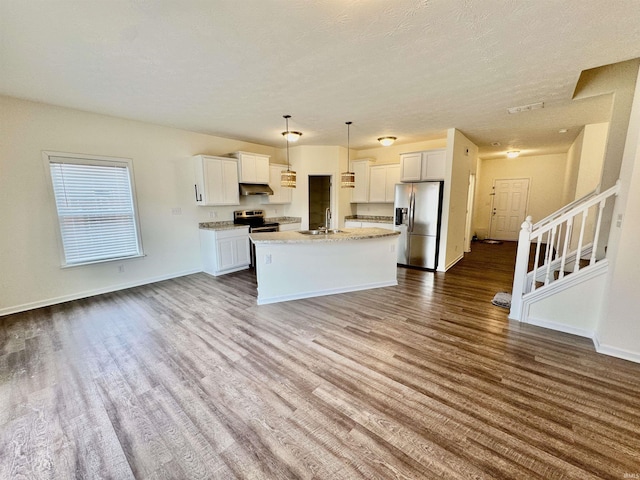 kitchen featuring dark wood finished floors, open floor plan, stainless steel appliances, under cabinet range hood, and a sink