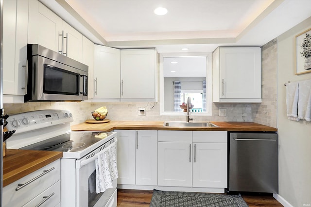 kitchen with white cabinetry, wood counters, appliances with stainless steel finishes, and a sink