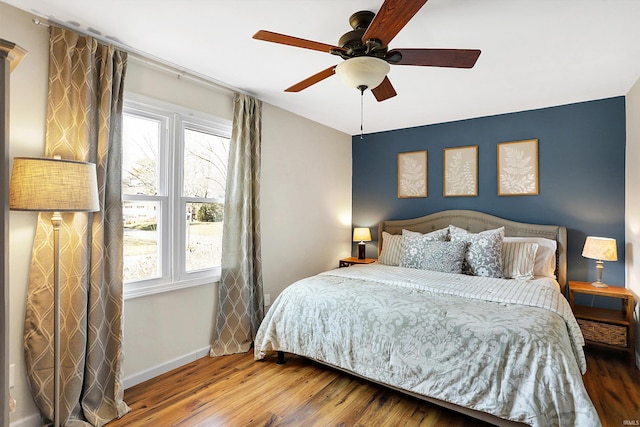 bedroom featuring a ceiling fan, baseboards, and wood finished floors