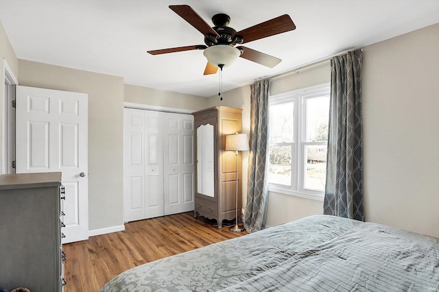 bedroom featuring a ceiling fan, a closet, baseboards, and wood finished floors