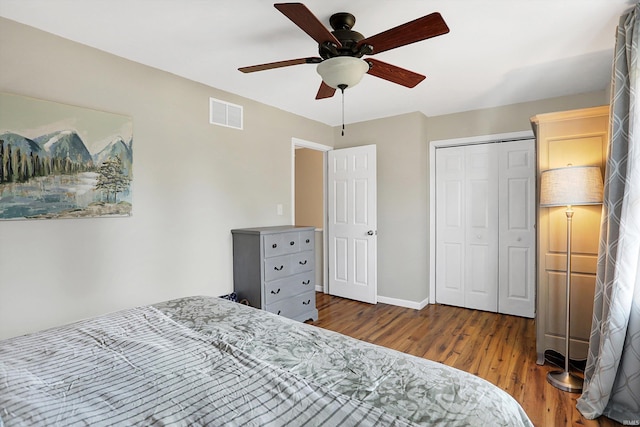 bedroom with baseboards, visible vents, ceiling fan, wood finished floors, and a closet