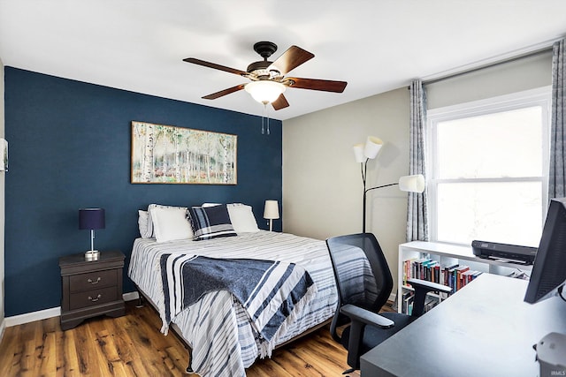 bedroom with ceiling fan, baseboards, and wood finished floors