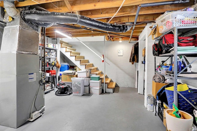 unfinished basement featuring stairway and heating unit