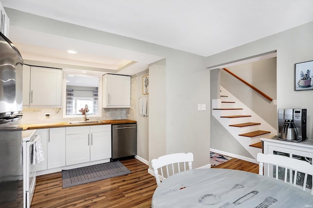 kitchen with butcher block countertops, a sink, white cabinets, dishwasher, and white range with electric cooktop