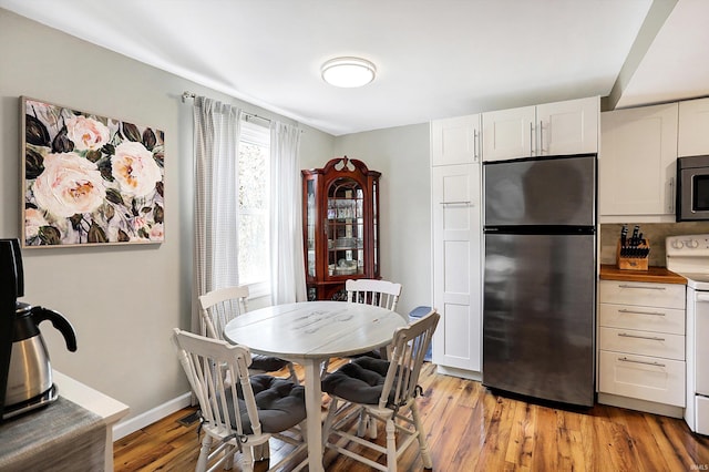 dining space with light wood-type flooring and baseboards