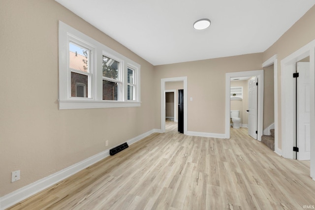 spare room with light wood finished floors, stairway, visible vents, and baseboards