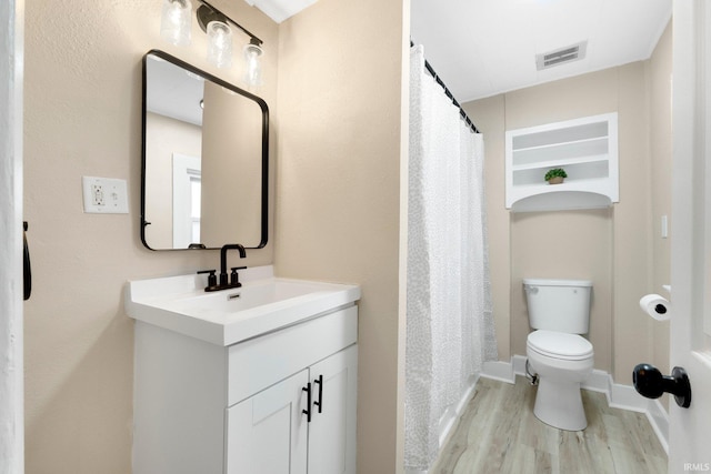 bathroom featuring toilet, wood finished floors, visible vents, vanity, and baseboards