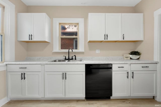 kitchen with black dishwasher, light countertops, light wood-style floors, white cabinetry, and a sink