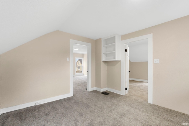 additional living space with carpet floors, baseboards, visible vents, and lofted ceiling