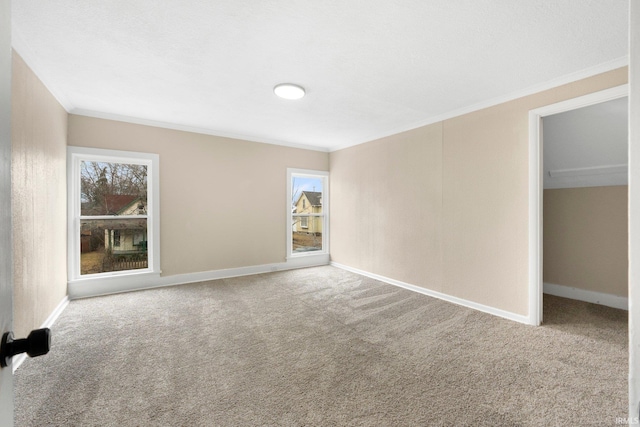 unfurnished bedroom with baseboards, carpet flooring, a walk in closet, and crown molding