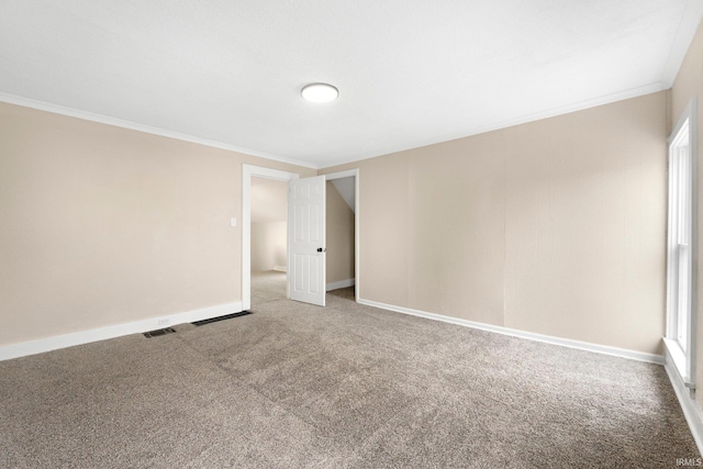 carpeted spare room featuring visible vents, crown molding, and baseboards