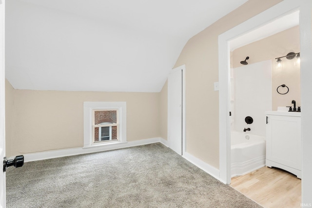 bathroom with lofted ceiling, vanity, washtub / shower combination, and baseboards