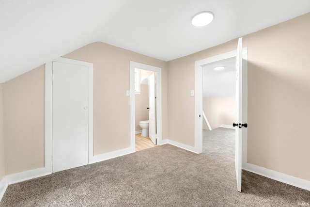 bonus room featuring lofted ceiling, light carpet, and baseboards