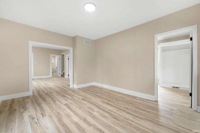 unfurnished room with light wood-type flooring, visible vents, and baseboards