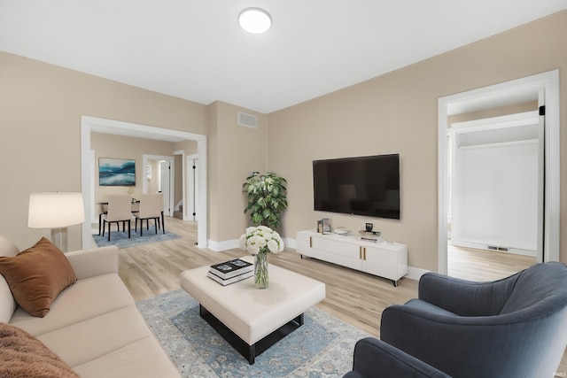 living area with light wood-style floors, visible vents, and baseboards