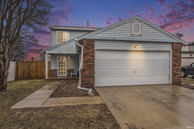 traditional home with a garage, concrete driveway, brick siding, and fence