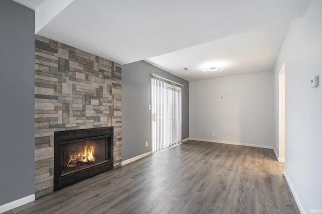 unfurnished living room with a fireplace, baseboards, and wood finished floors